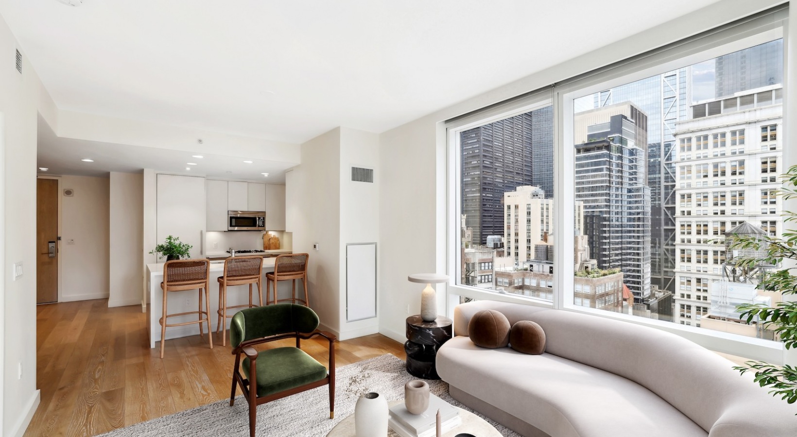 Modern living room and open kitchen at 19 Dutch with large windows and skyline views over Lower Manhattan.