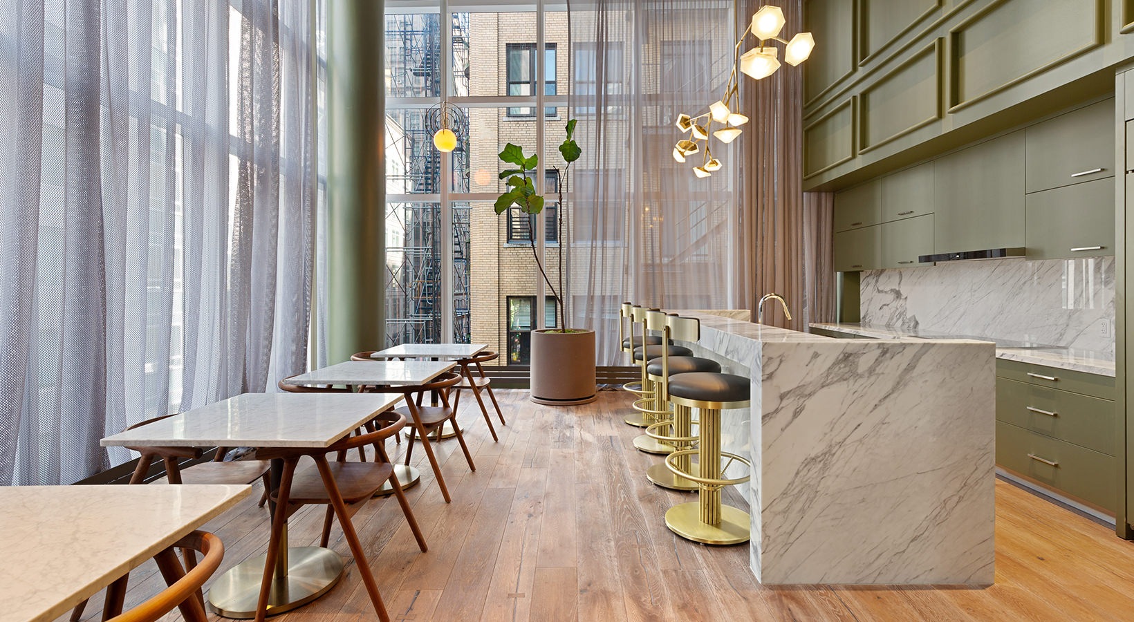 Resident kitchen at 19 Dutch with marble counters, brass bar stools, and café-style seating in Lower Manhattan.