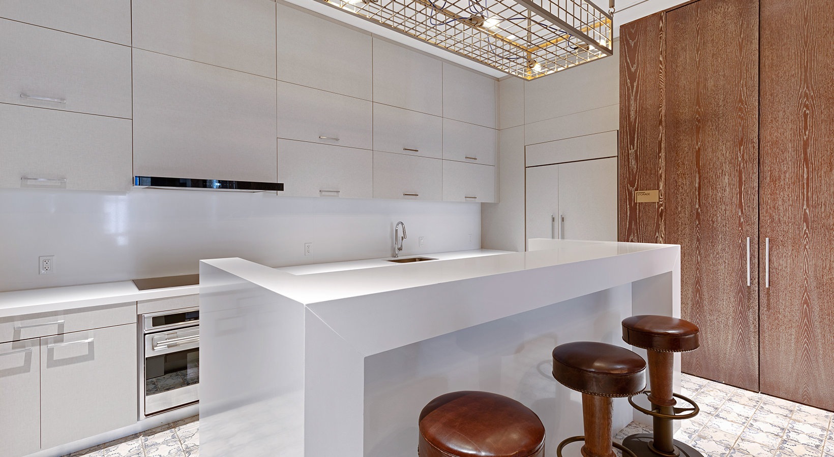Modern residential kitchen with sleek white countertops, built-in appliances, and bar seating at 19 Dutch in Lower Manhattan.