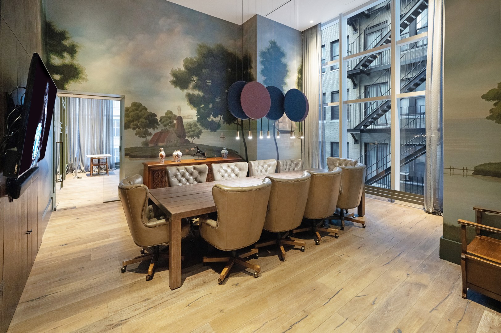 Conference room at 19 Dutch with leather chairs, a wood table, and scenic mural artwork in Lower Manhattan.