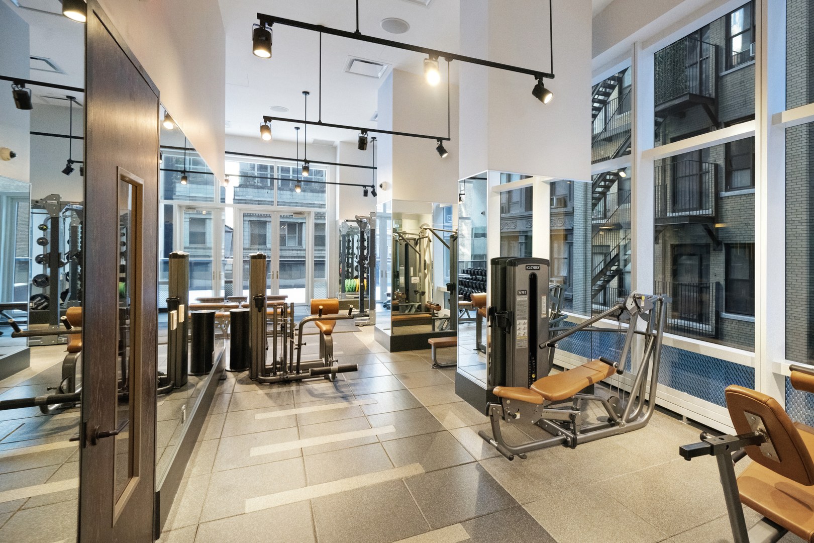19 Dutch fitness club with strength-training machines, mirrored walls, and floor-to-ceiling windows overlooking Downtown Manhattan.