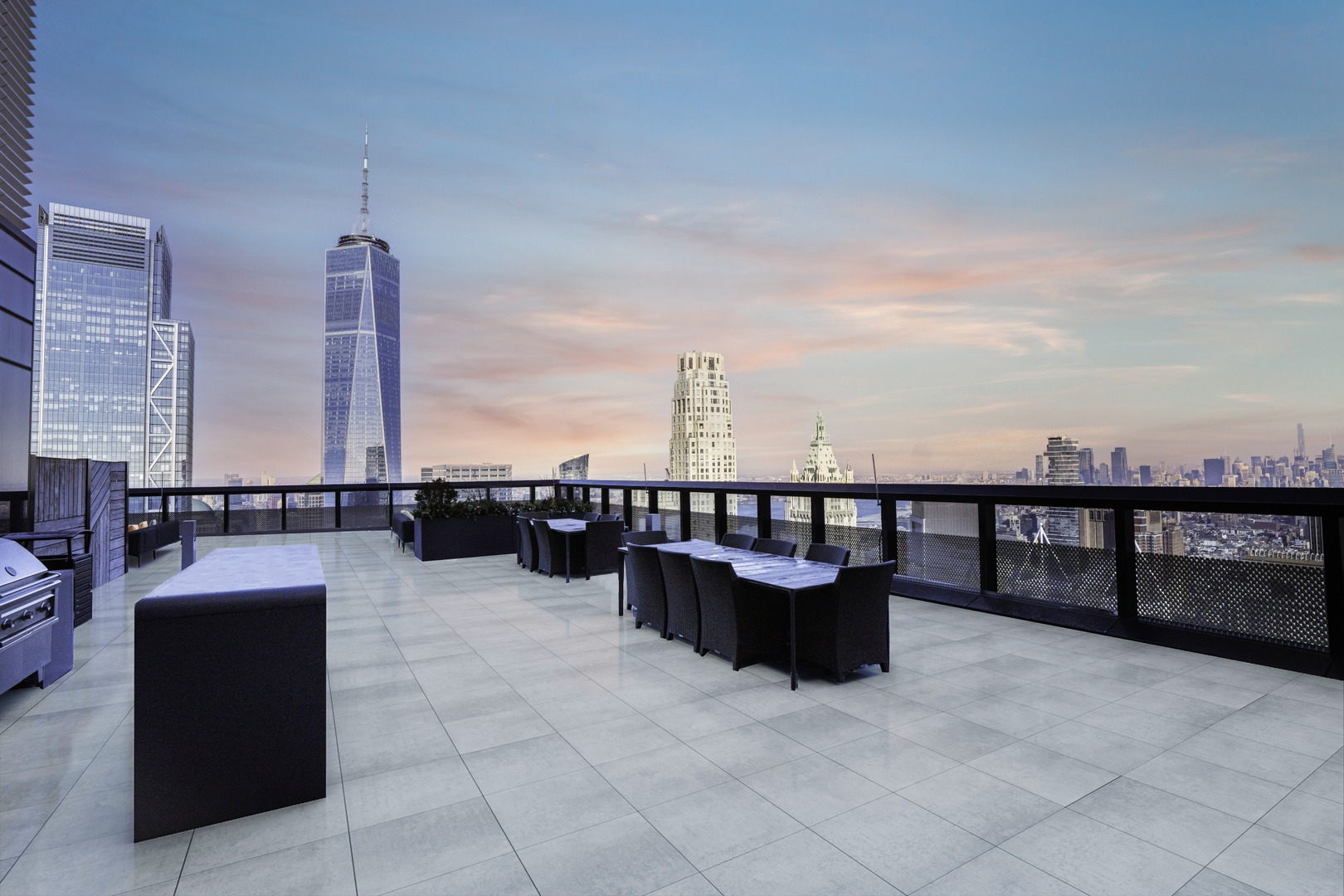 Night view of Rooftop terrace with dining tables and views of Lower Manhattan and One World Trade Center at 19 Dutch