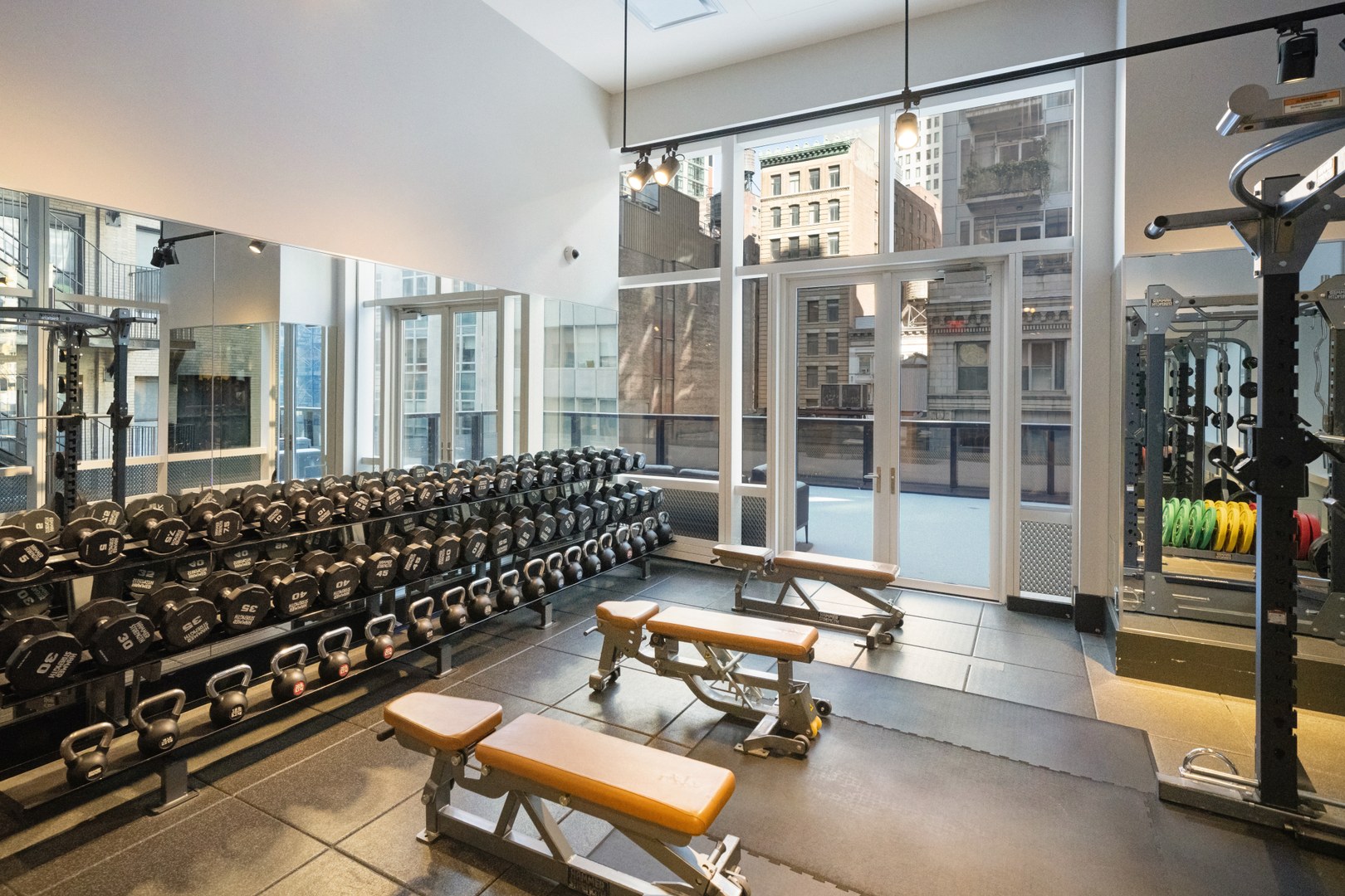Strength-training area at 19 Dutch with dumbbells, benches, kettlebells, and city views.